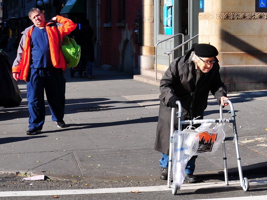 A woman in a beret walking across the street using an assistive device.